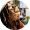 Two women sitting closely together, looking intently in the same direction, appearing engaged and focused. The background is slightly blurred, suggesting an indoor setting.