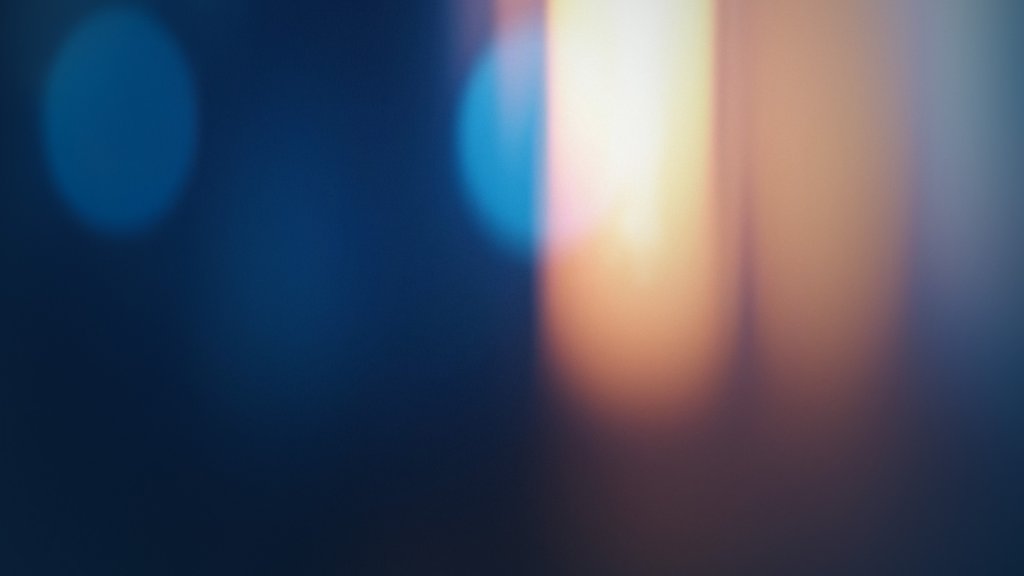 Abstract image with a blurred blend of dark blue and orange light, creating a soft, dreamy atmosphere. No distinct objects or shapes are visible.