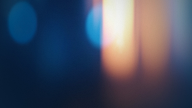 Abstract image with a blurred blend of dark blue and orange light, creating a soft, dreamy atmosphere. No distinct objects or shapes are visible.