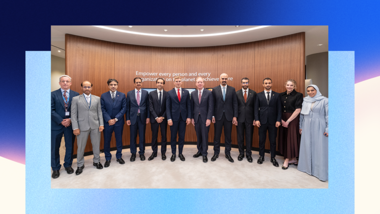 Twelve people in formal attire stand in a row for a group photo in front of a wooden wall with an inspirational quote. Most are men in suits; one woman wears a long dress and headscarf.
